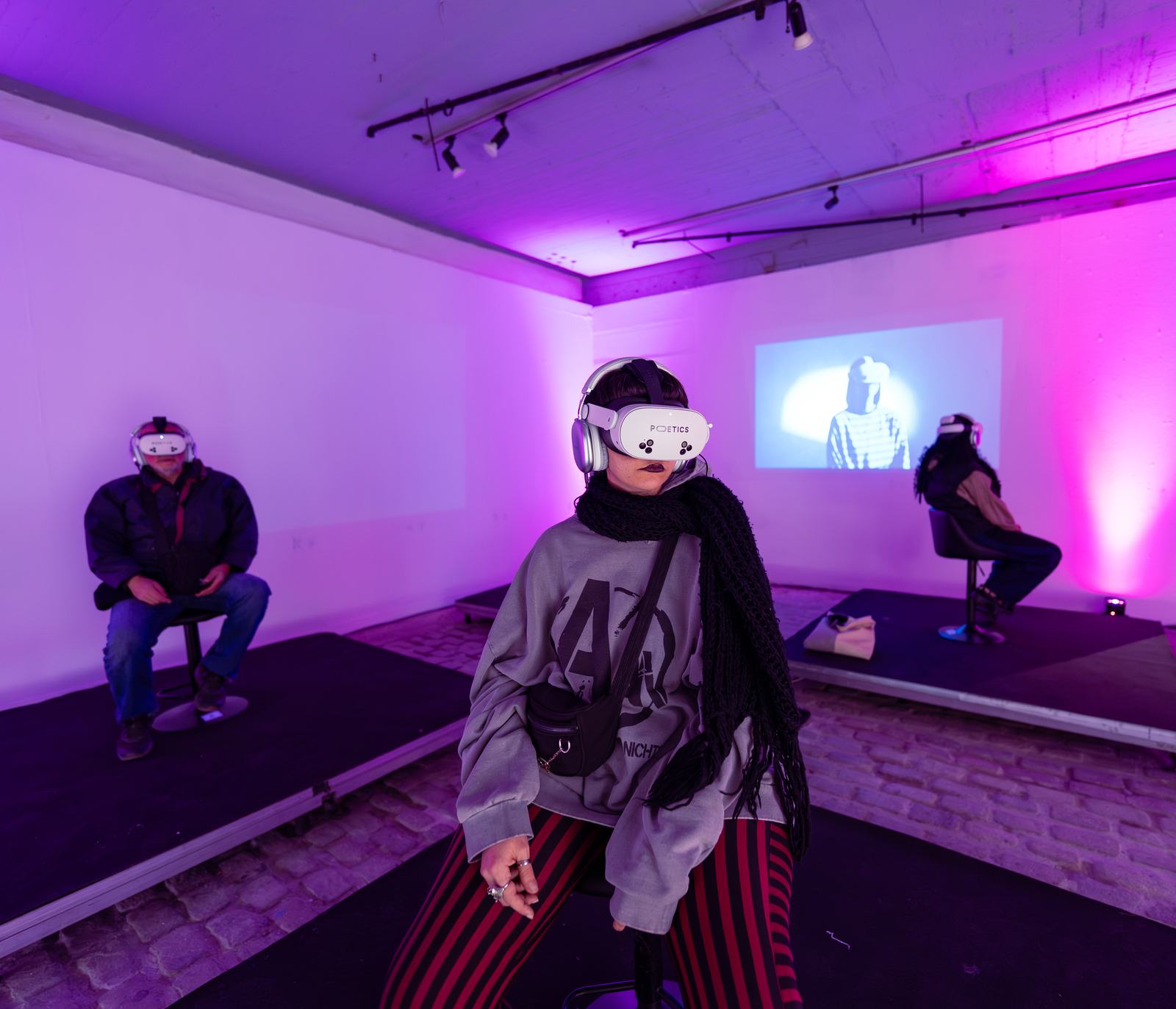 Three Poetics VR stations in a purple-lit venue