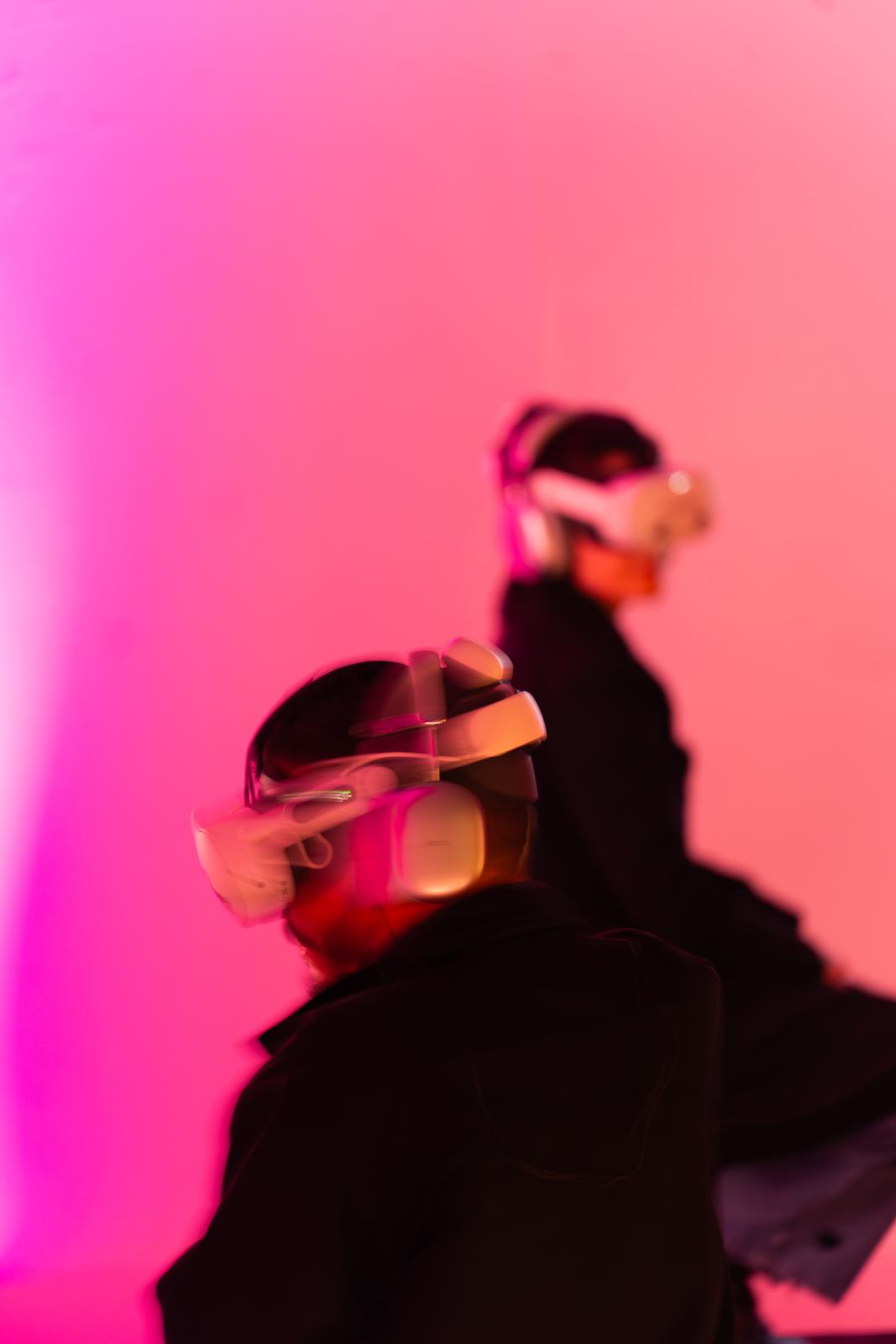 Two visitors wearing VR headsets in pink event lighting