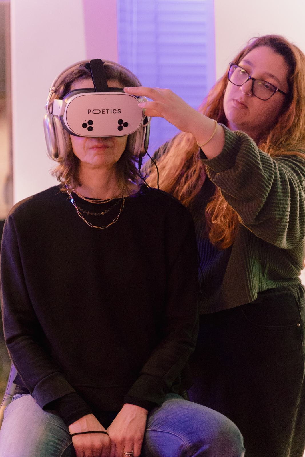 Operator fitting a Poetics VR headset on a seated visitor
